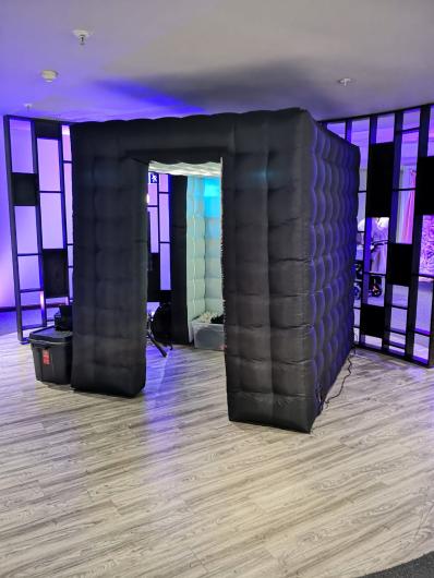 Black inflatable photo booth with purple event lighting